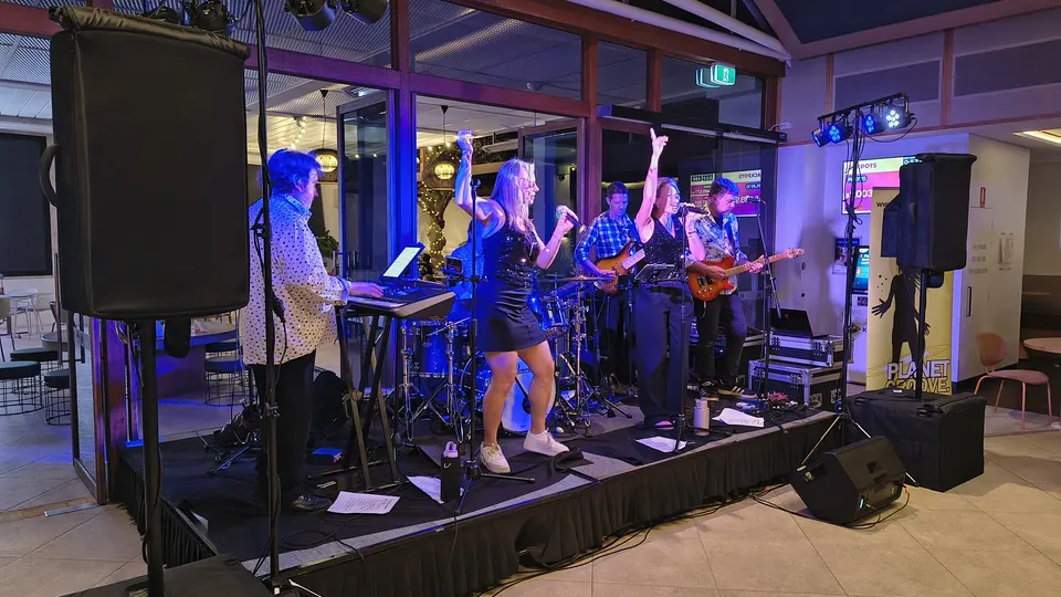 A band with two singers on a low stage in a club function room
