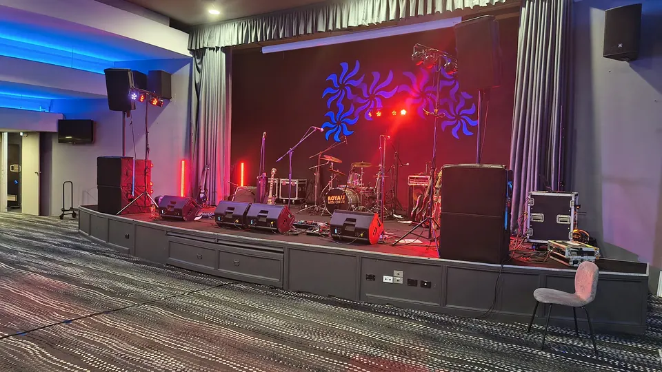 A stage set for the show: red uplights, a drum kit and speaker stacks either side
